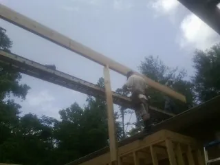 Carpenter setting a ridge beam over a new addition frame — Ice Dam Removal by Roofing Brothers in Jeremiah