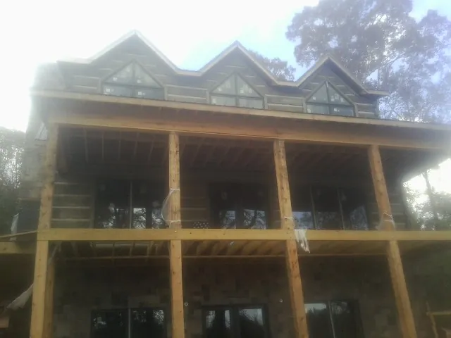 Dormers and porch framing on a large log home under construction — Roof Coating work by our crew in Jeremiah
