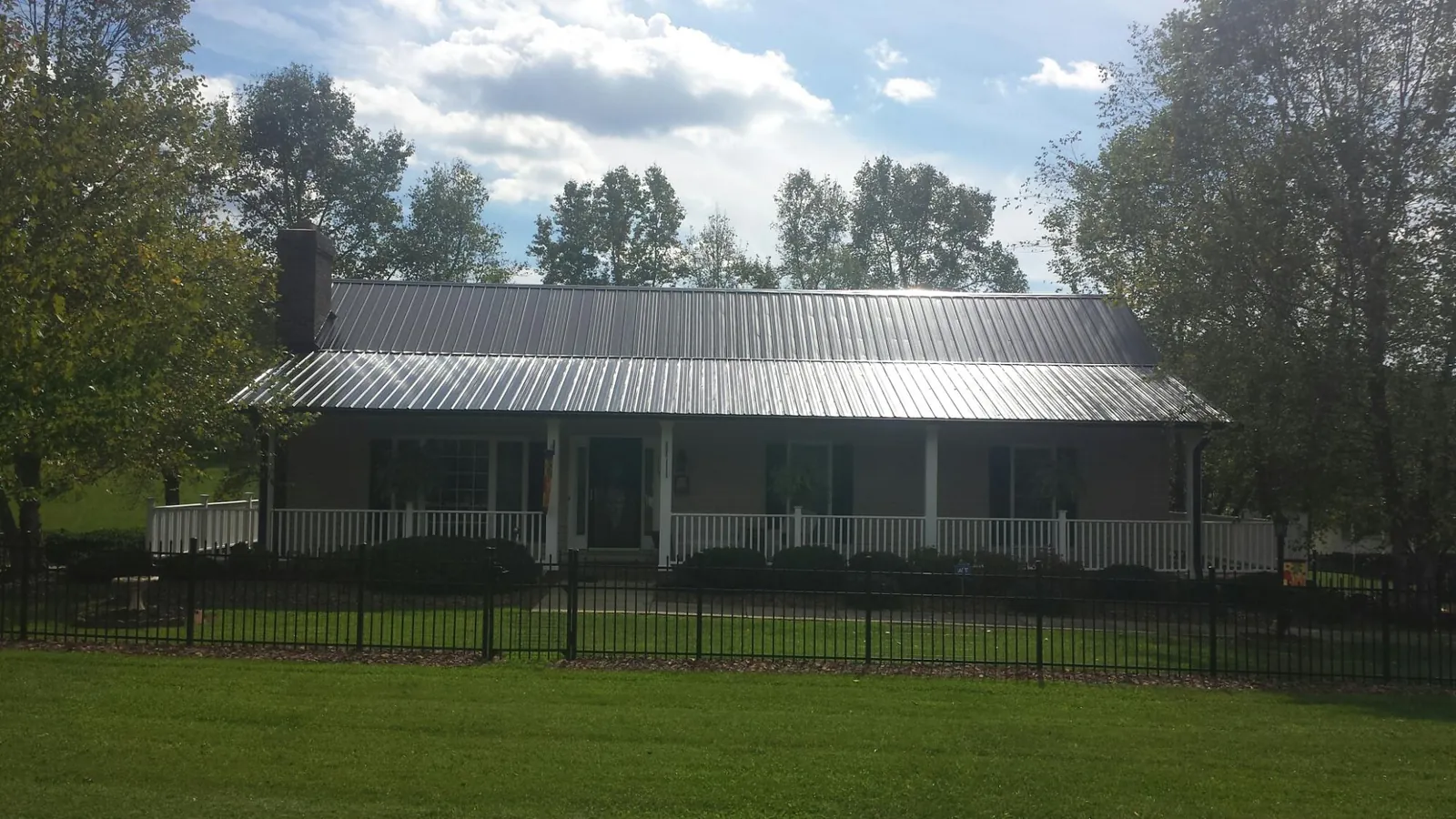 Gray metal roof on a brick ranch with a full width front porch — Gutter Guard Installation work by our crew in Jeremiah