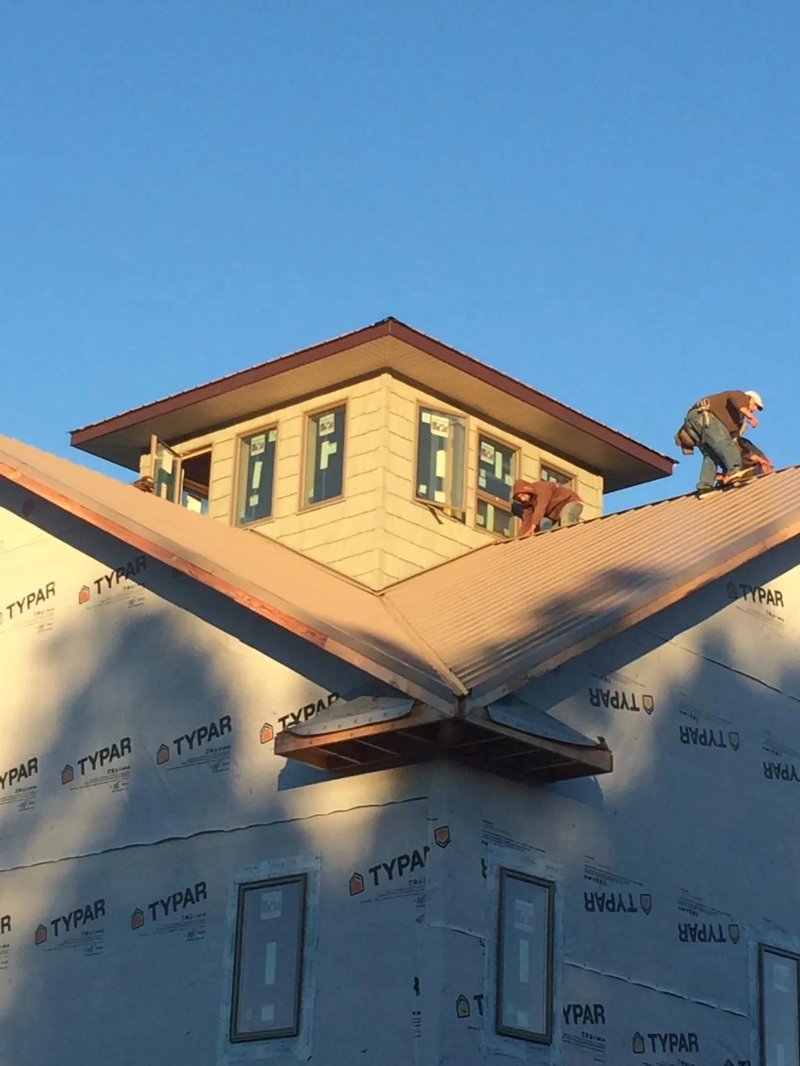 Roofers working around a rooftop cupola on a new metal roof at sunset — Roof Waterproofing in Jeremiah by Roofing Brothers